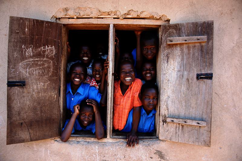 Bambini sorridenti affacciati alla finestra di una scuola in Camerun